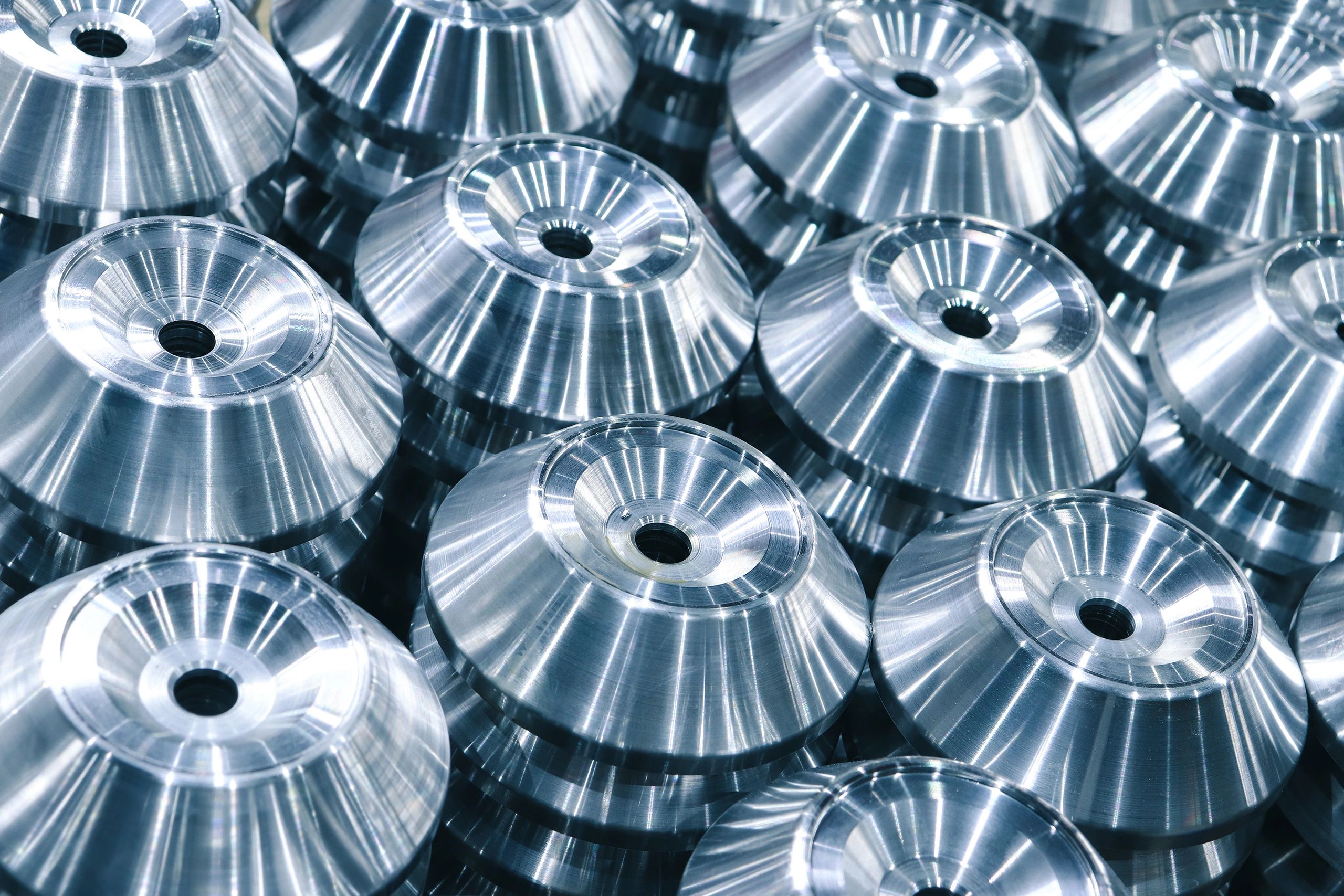 Metal products turned on a CNC milling machine, arranged in even rows, close-up with selective focus.